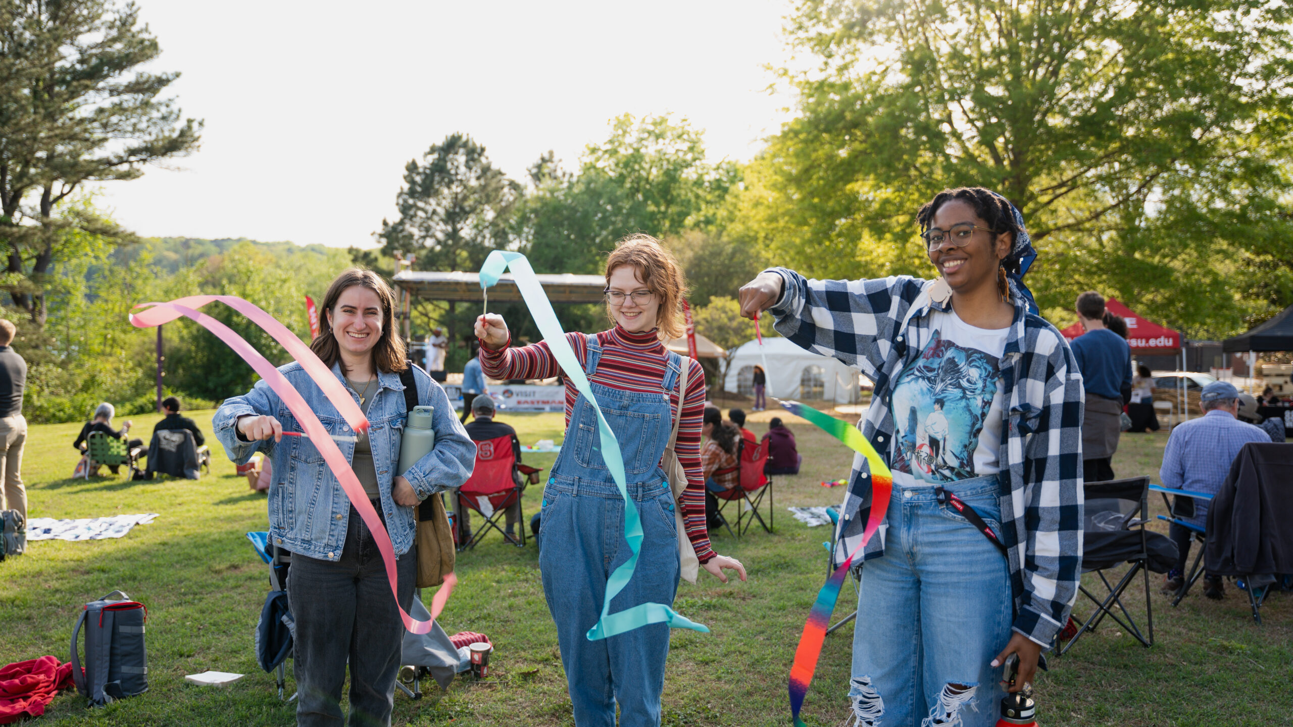 Three students twirl colorful ribbons at the outdoor concert called LIVE@Lake Raleigh