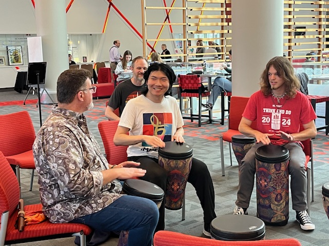 A small group of people playing in a drum circle.